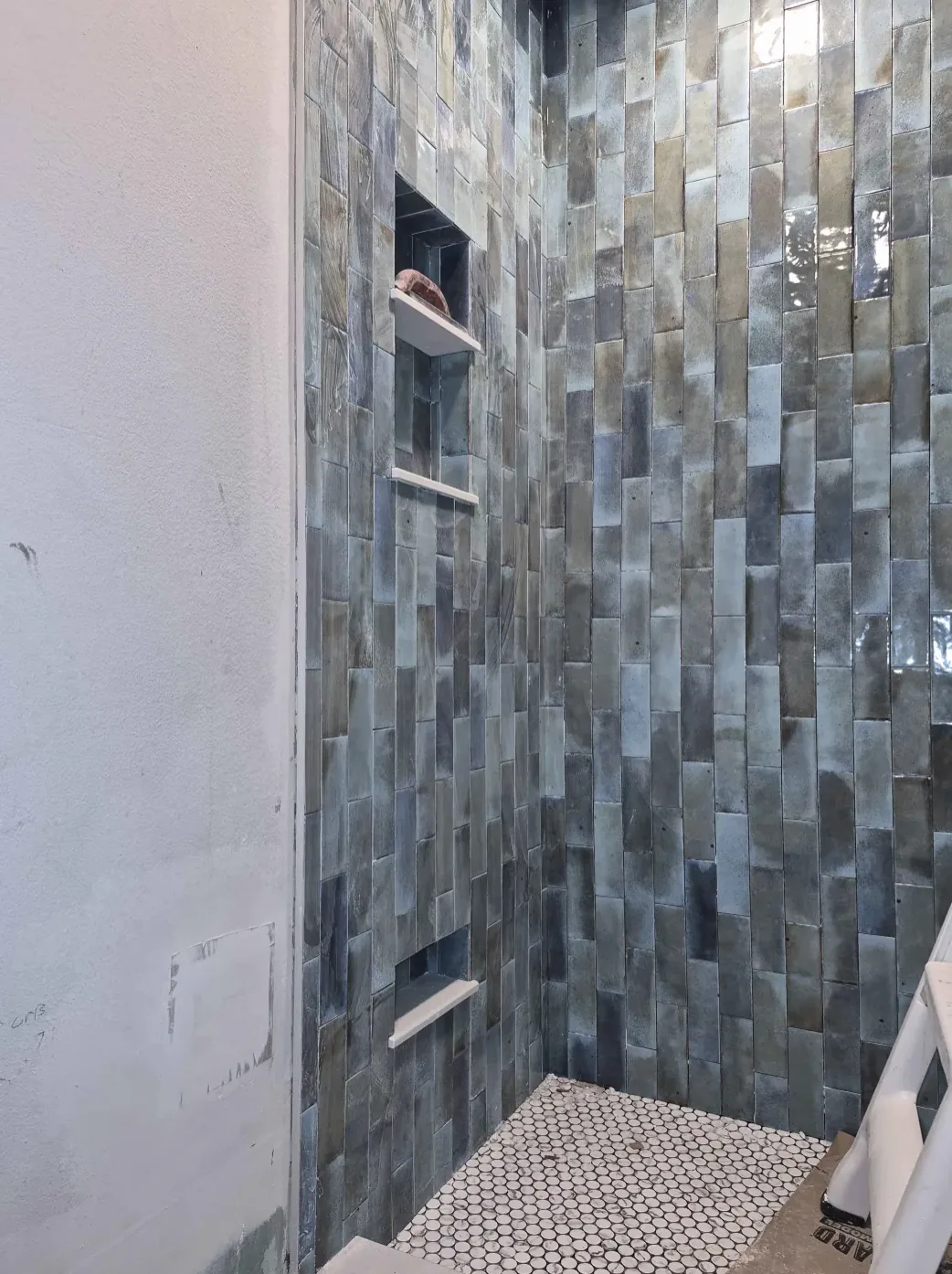 Shower wall in blue vertical tile with a recessed niche