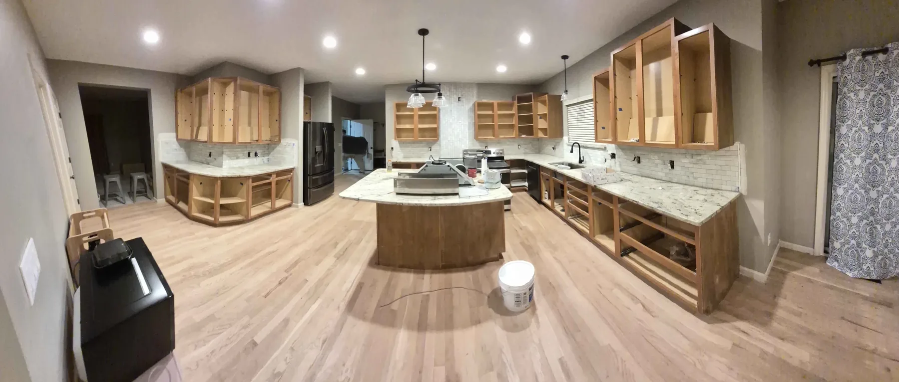 Wide view of an open-concept kitchen and living area with a new hardwood floor