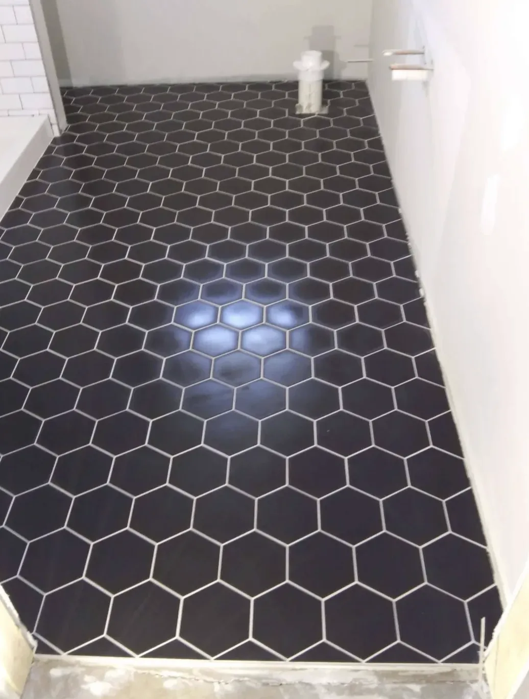 Black hexagon tile floor in a narrow bathroom