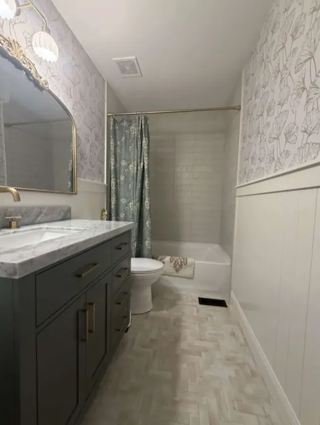 Bathroom with a patterned tile floor, a dark vanity and wainscoting