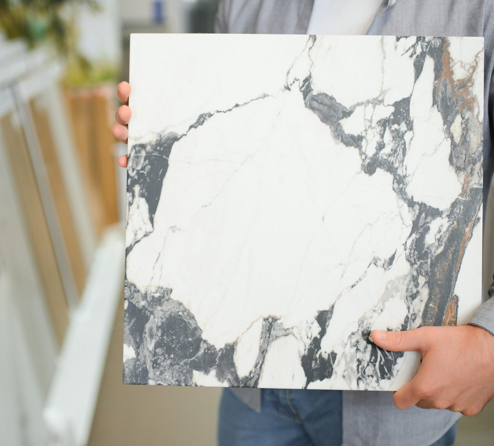 Male architect or interior designer choosing ceramic texture sample from swatch board in design studio. Floor and wall finishing material for architecture and construction industry.