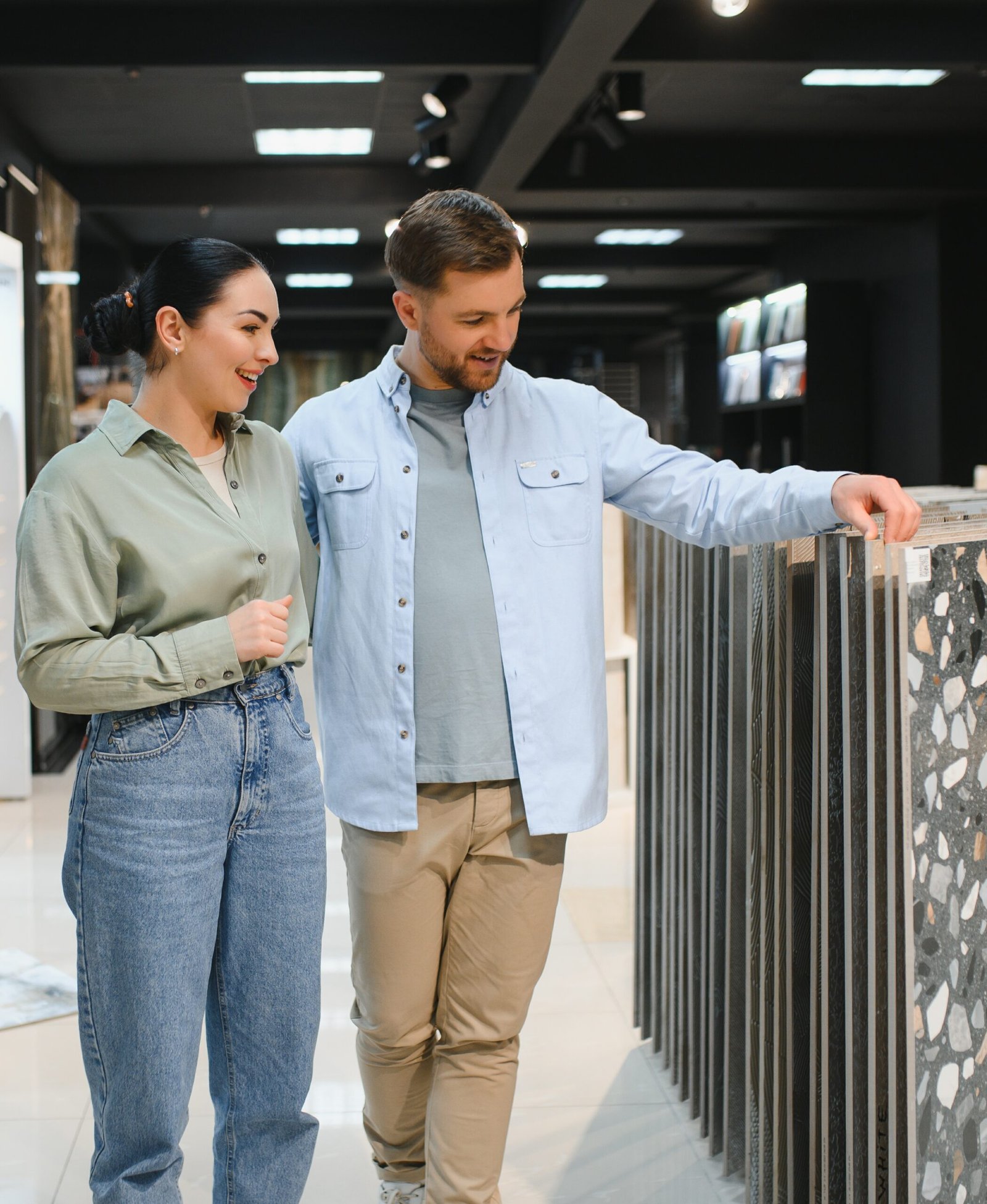 Young couple browsing ceramic tiles in a modern hardware store, selecting options for their apartment renovation and home improvement project